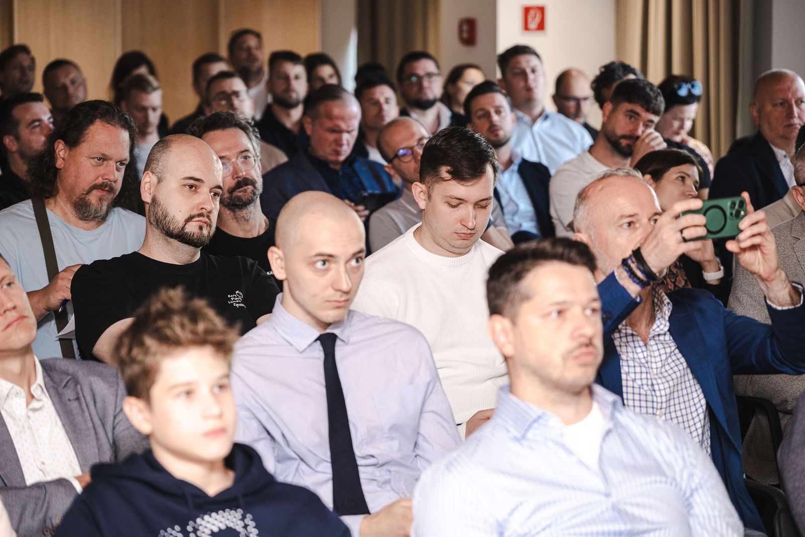 Pozorné publikum v prvých radoch, jeden z účastníkov si fotí slajd